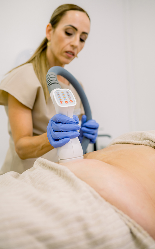 Professional female specialist applying fat freezing technology with special lipolysis machine in beauty salon